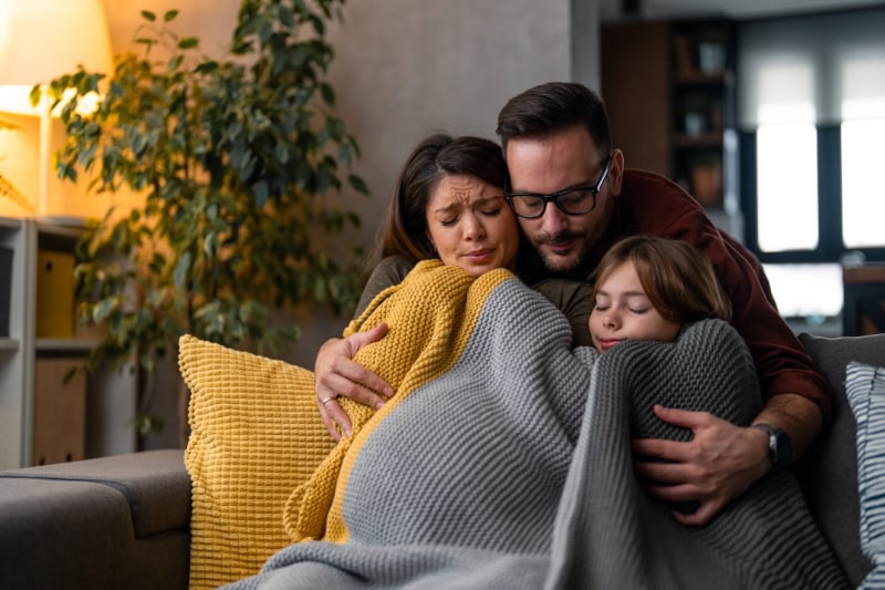 Family huddled together on couch due to furnace not heating their entire home.